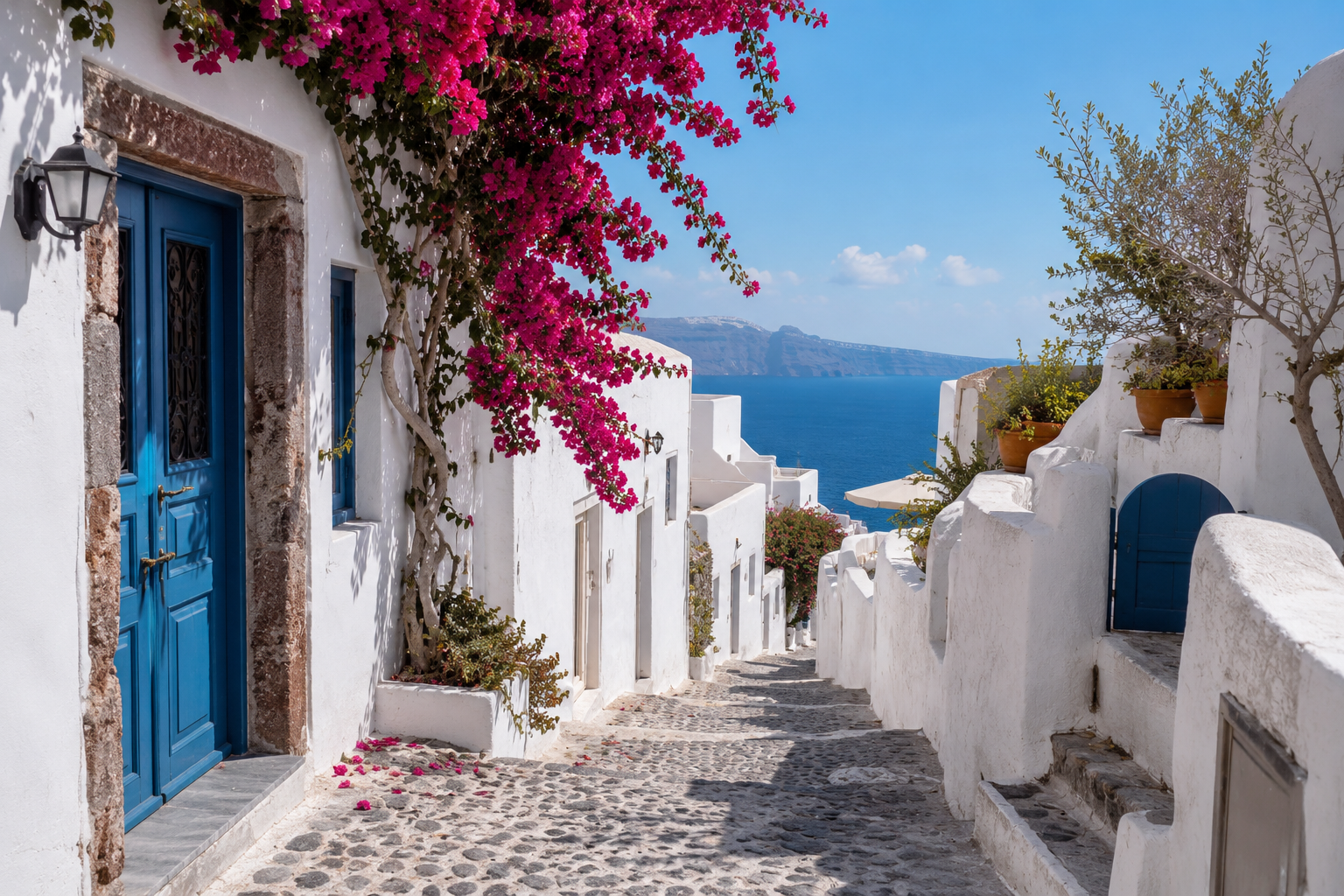 Calle tradicional de Oia, Santorini, con buganvillas, casas blancas y vistas al mar Egeo.